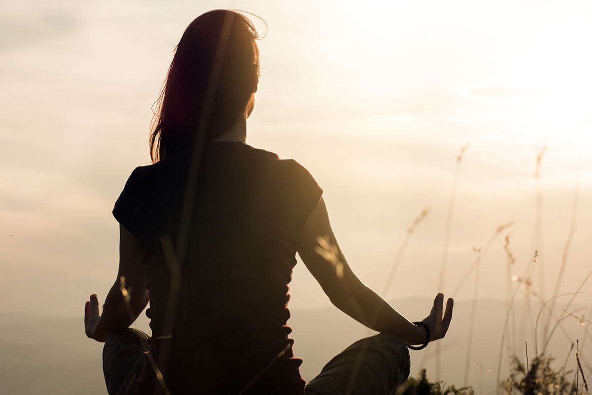 Silhouette of young woman practicing yoga outdoors